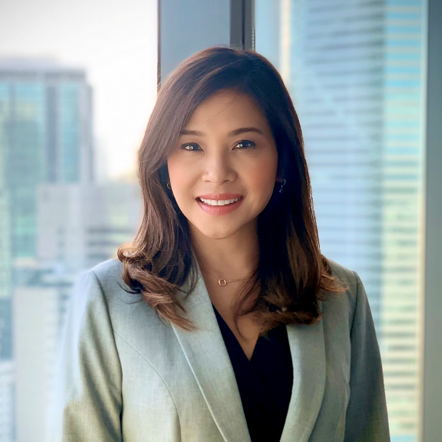 Person smiling in an office setting with a city view.