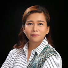 Portrait of a woman with brown hair, wearing a striped shirt, set against a dark background.