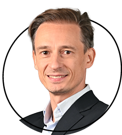 Smiling person in a suit against a white background.