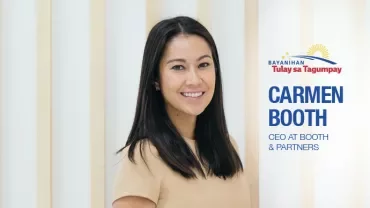 Smiling woman standing indoors with wooden panels in the background.