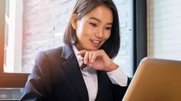 Businesswoman smiling while working on a laptop indoors.
