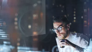 Man analyzing data on a computer, surrounded by digital graphs and charts.