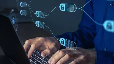Person typing on a laptop with blockchain technology visuals overlayed.