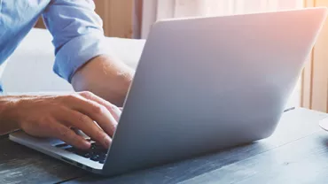 Person typing on a laptop next to a cup of coffee.