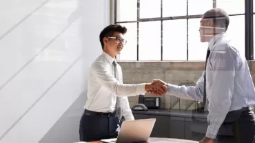 Two businessmen shaking hands in a bright office.