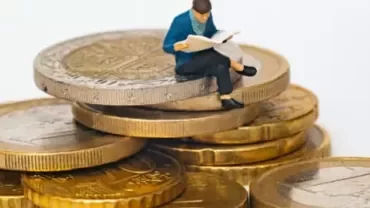 Miniature figure sitting on stacked coins representing highest paying jobs and financial growth opportunities