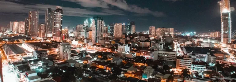 A vibrant city skyline at night with tall buildings and bright lights.