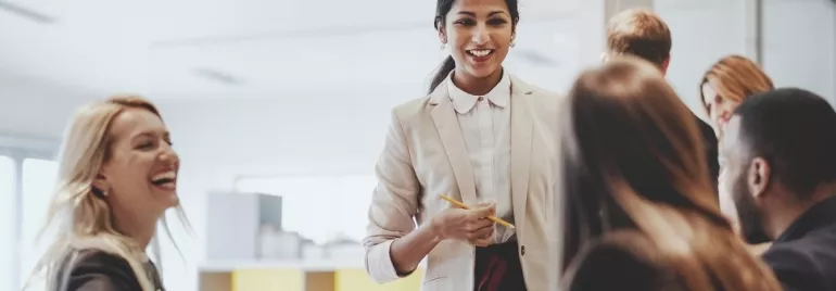 A woman leading a team meeting with smiling colleagues.