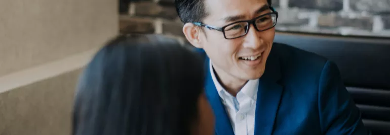 Person in a blue suit smiling during a conversation in a modern office.