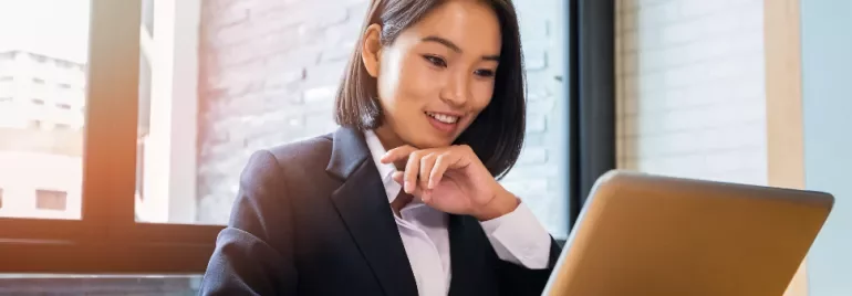 Businesswoman smiling while working on a laptop indoors.