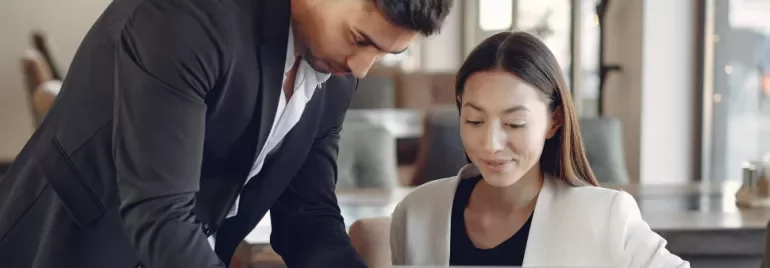 Man and woman collaborating on a laptop in an office.