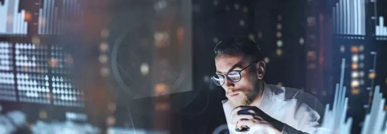 Man analyzing data on a computer, surrounded by digital graphs and charts.