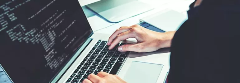 Person typing on a laptop with code on the screen.