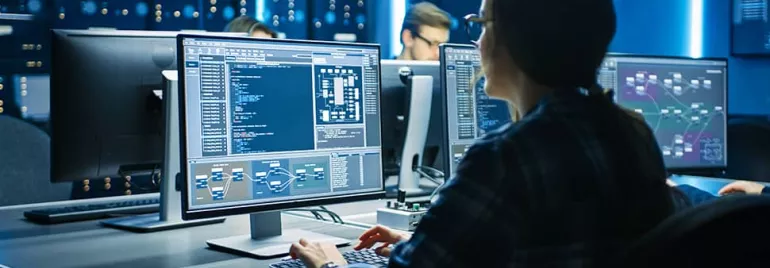 Person working at a computer with code on the screen in a tech office.