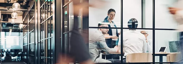 Colleagues in a modern office meeting room, engaged in discussion.