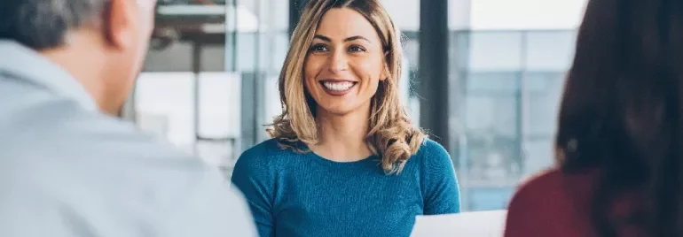 Woman in blue shirt smiling during a meeting.