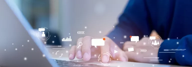 Person typing on a laptop with digital icons floating above the keyboard.