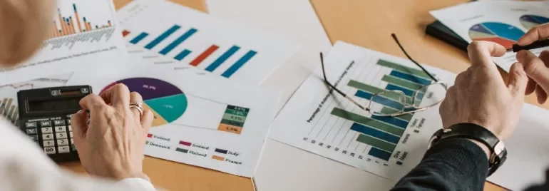 Two people reviewing financial charts and graphs at a desk.