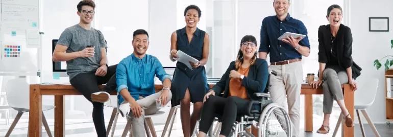 A diverse team of seven people smiling and posing in a modern office environment.