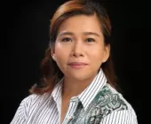 Portrait of a woman with brown hair, wearing a striped shirt, set against a dark background.