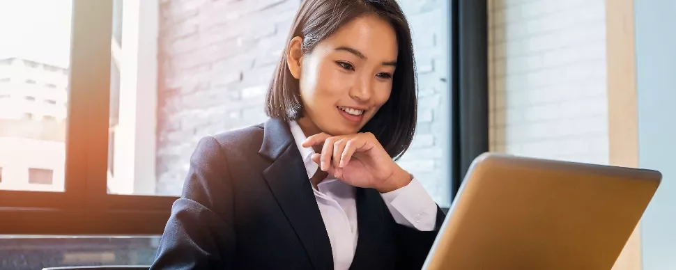 Businesswoman smiling while working on a laptop indoors.