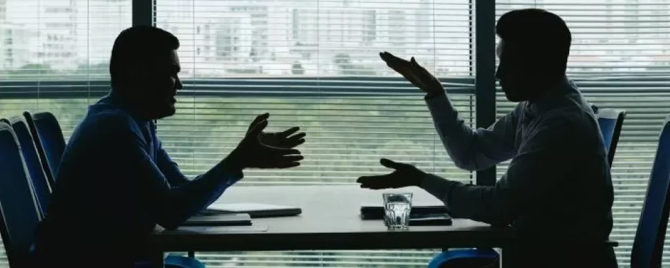 Silhouette of two business professionals engaged in conversation at a table, emphasising collaboration and discussion.