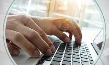 Hands typing on a laptop keyboard near a sunlit window.