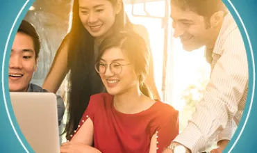 Group of people smiling and looking at a laptop screen together.