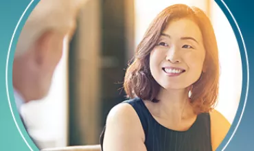 Woman smiling while listening to a conversation in a professional setting.