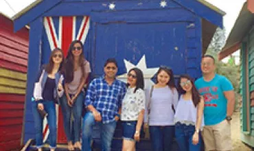 Group of people posing in front of a colorful beach hut.