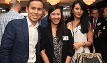 Group of people smiling at a networking event with warm lighting.