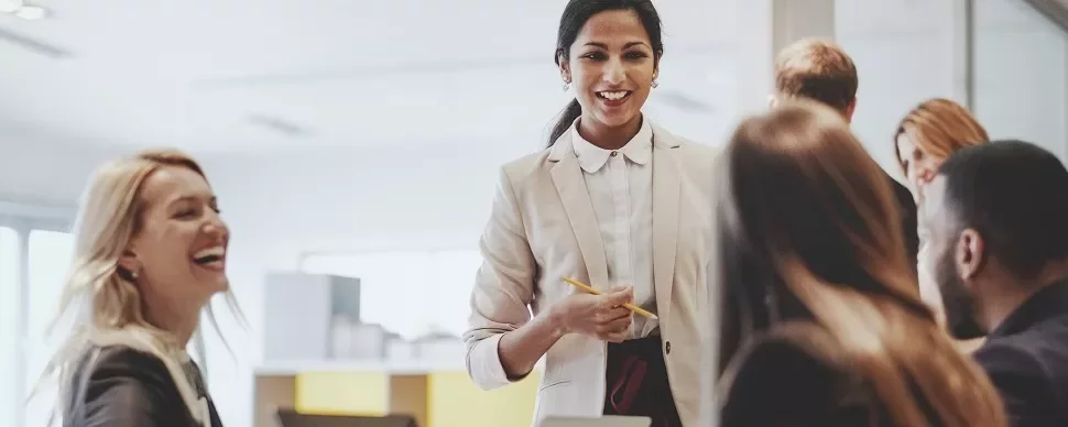 A woman leading a team meeting with smiling colleagues.