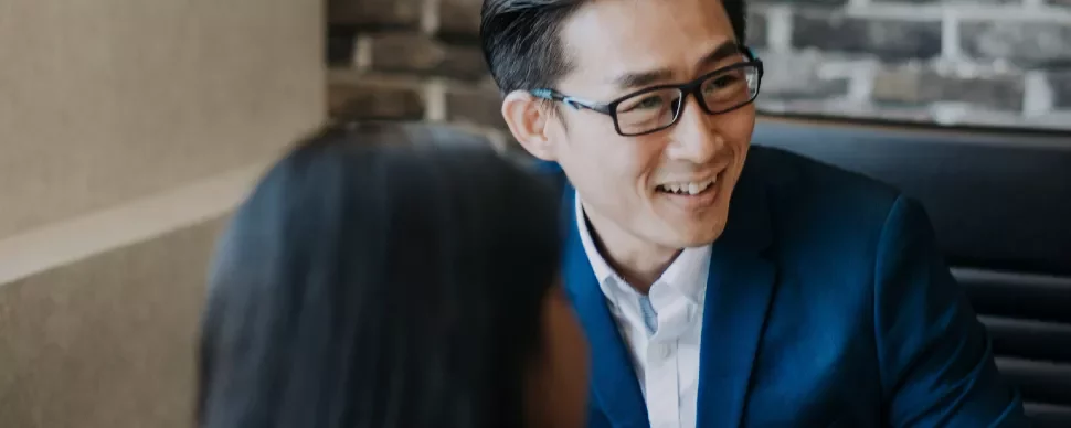 Person in a blue suit smiling during a conversation in a modern office.