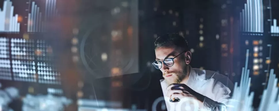 Man analyzing data on a computer, surrounded by digital graphs and charts.