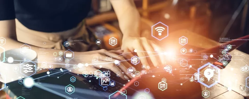 Person typing on a laptop with holographic technology icons overlayed