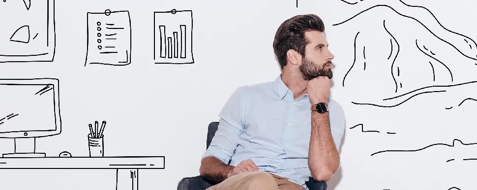 Man sitting and thinking in front of wall with drawings of graphs and landscapes.