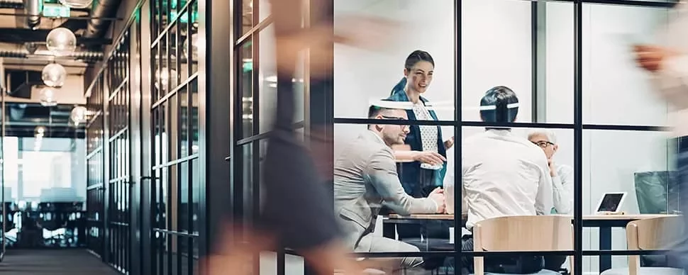 Colleagues in a modern office meeting room, engaged in discussion.