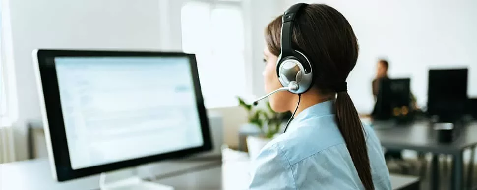 Person at computer wearing a headset, working in a call center.