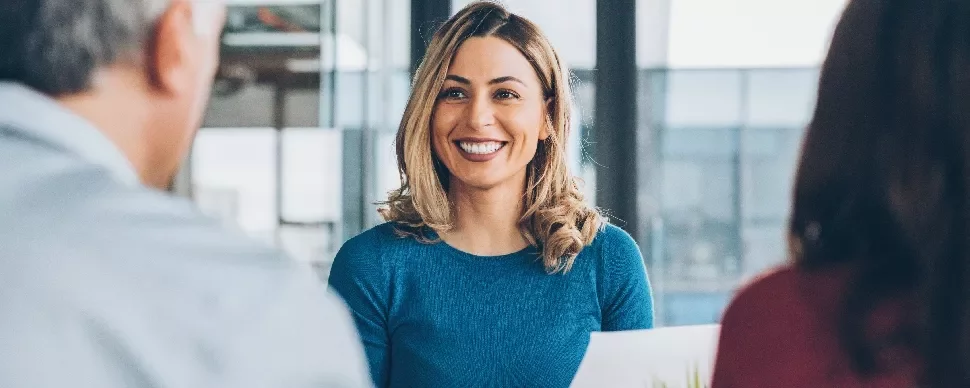 Woman in blue shirt smiling during a meeting.